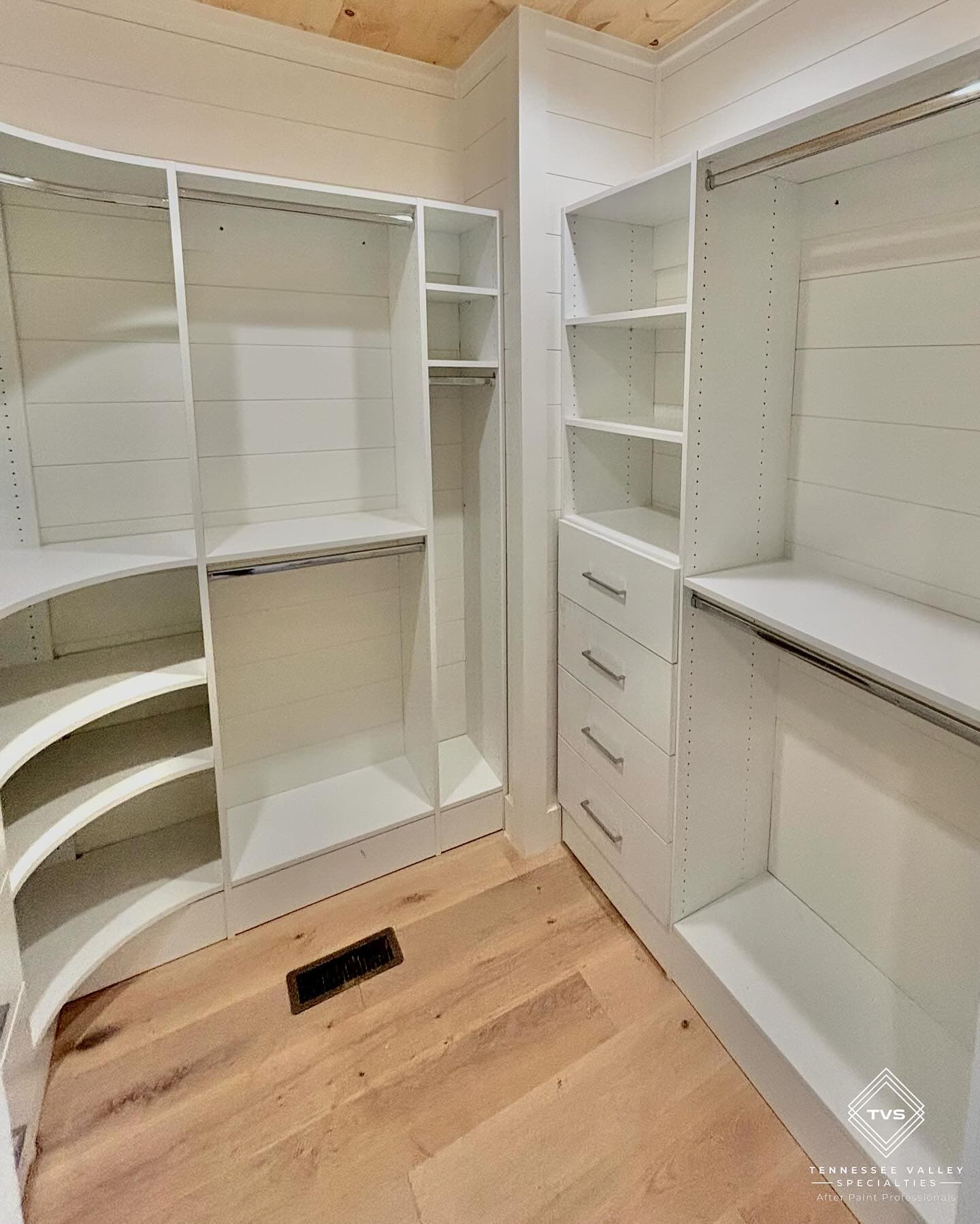 Custom walk-in closet with white built-ins—shelving, drawers, and hanging storage.