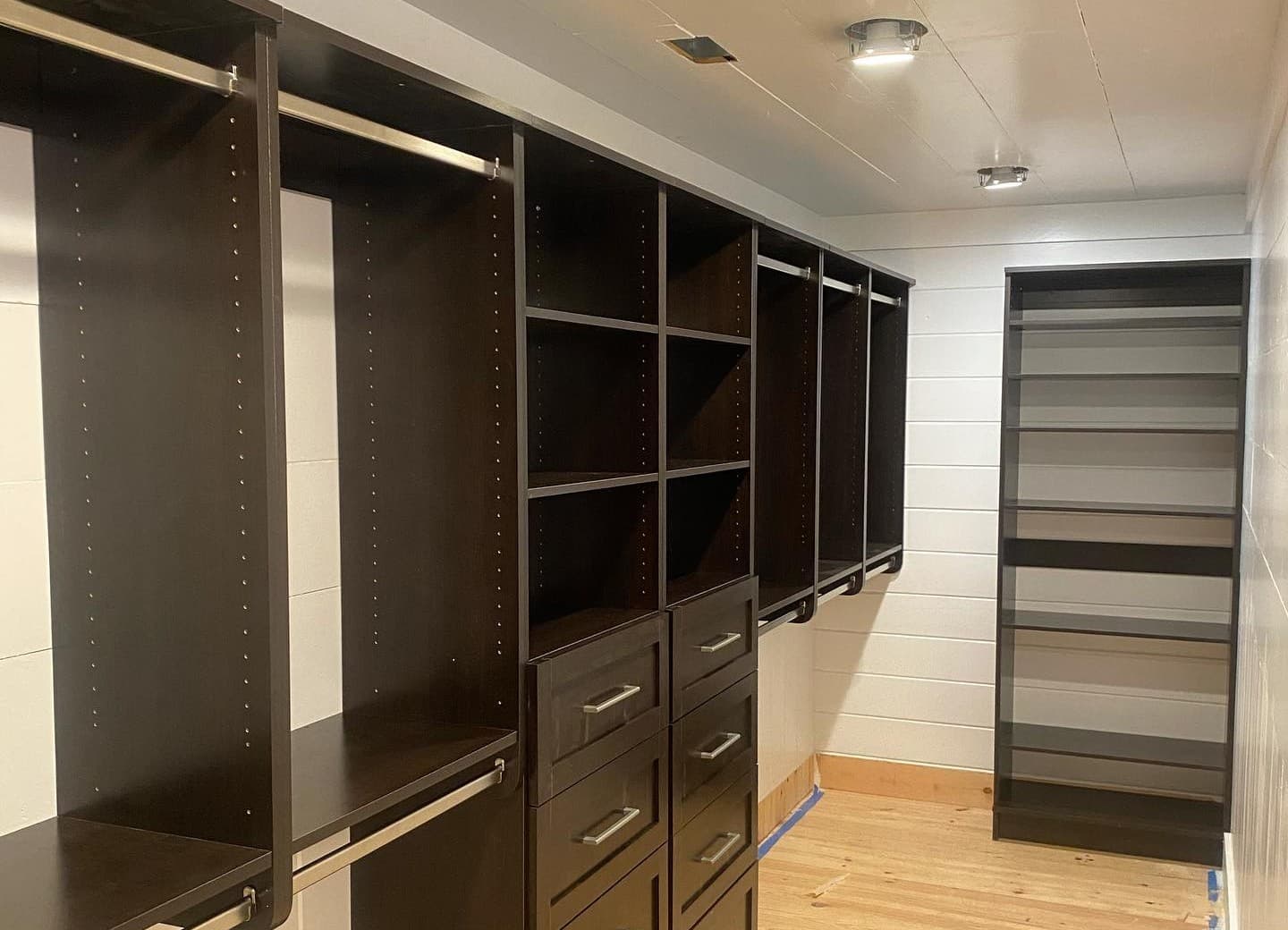 Custom walk-in closet with built-in shelving, hanging rods, and drawer storage in a finished room.