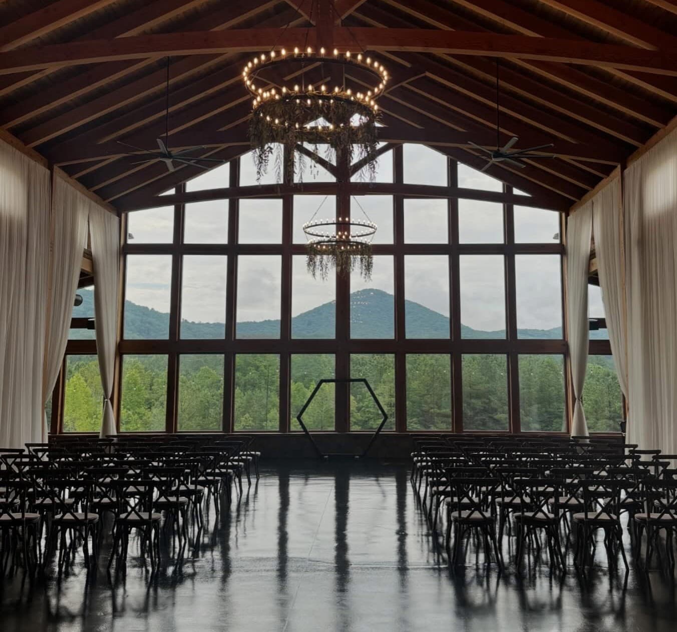Large-scale interior glazing in a high-ceilinged venue—floor-to-ceiling window wall with forest and mountain views.