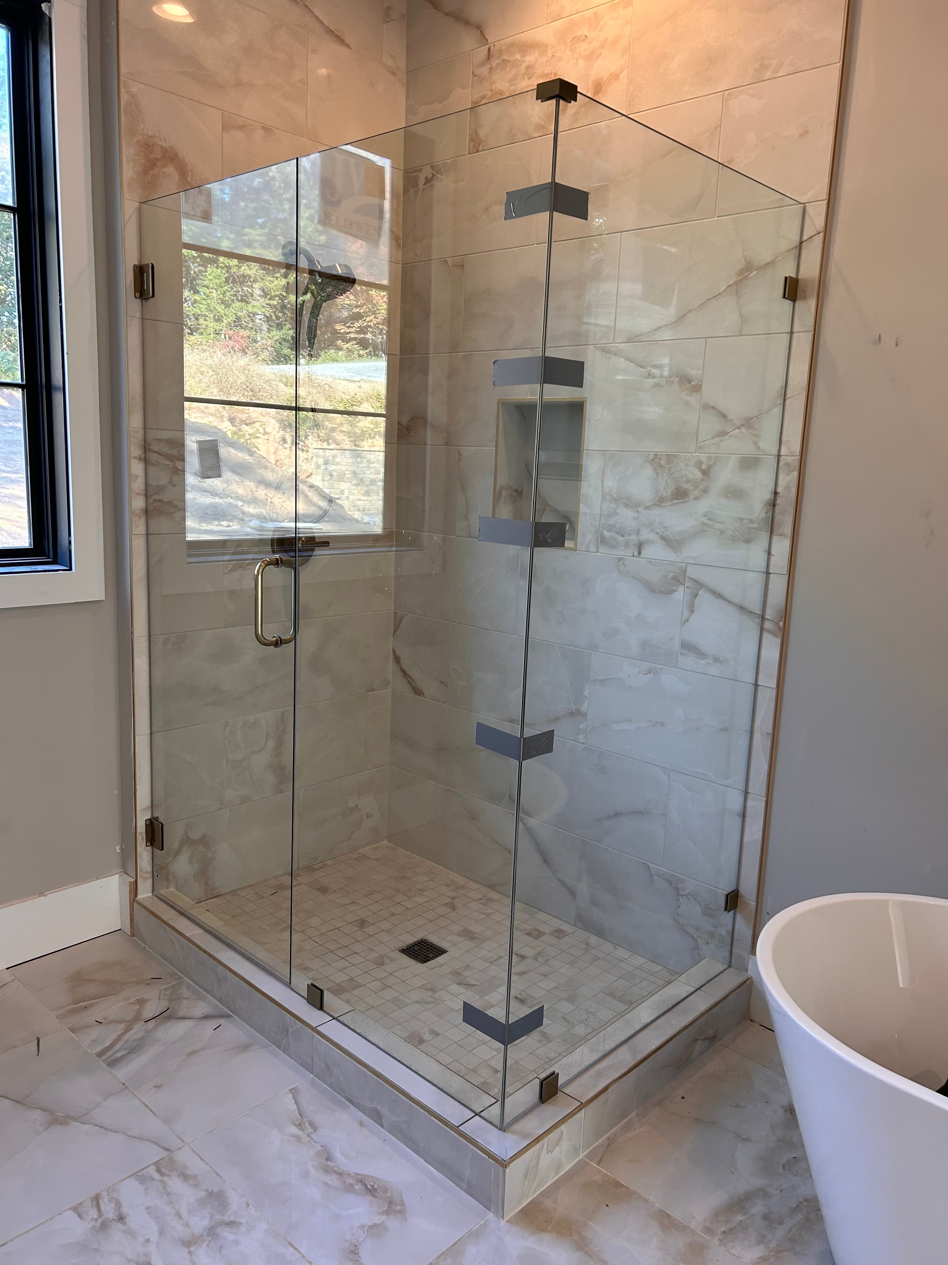 Glass shower door and panel installation with tile surround.
