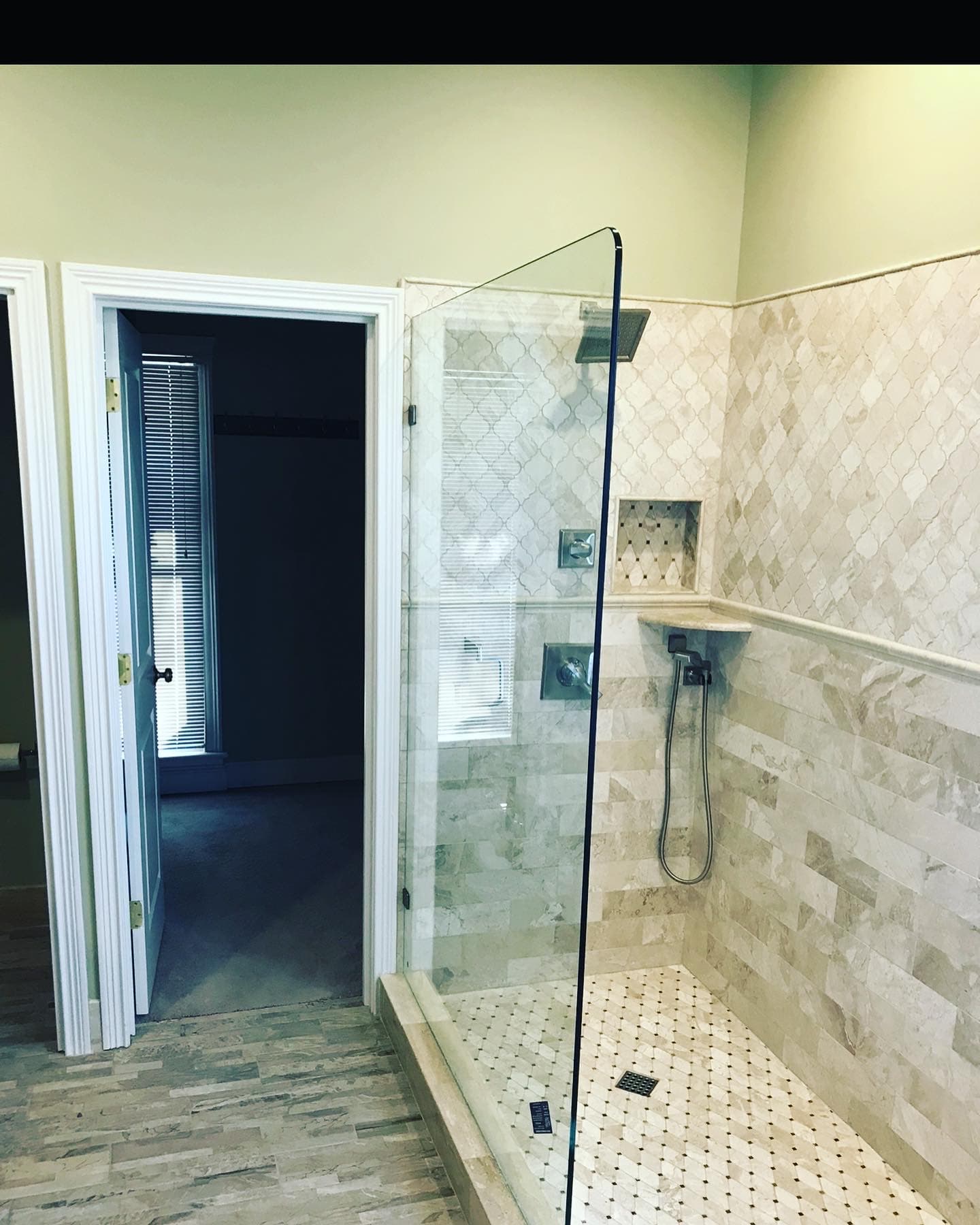 Frameless shower glass—door panel, polished hardware, and tile surround detail.