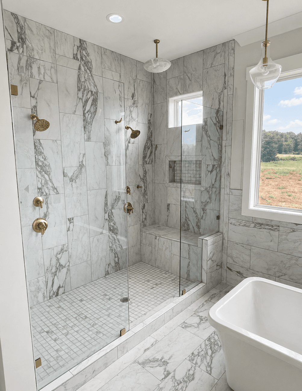 Walk-in shower with marble-look tile, glass enclosure, gold hardware, built-in bench, and mosaic floor.