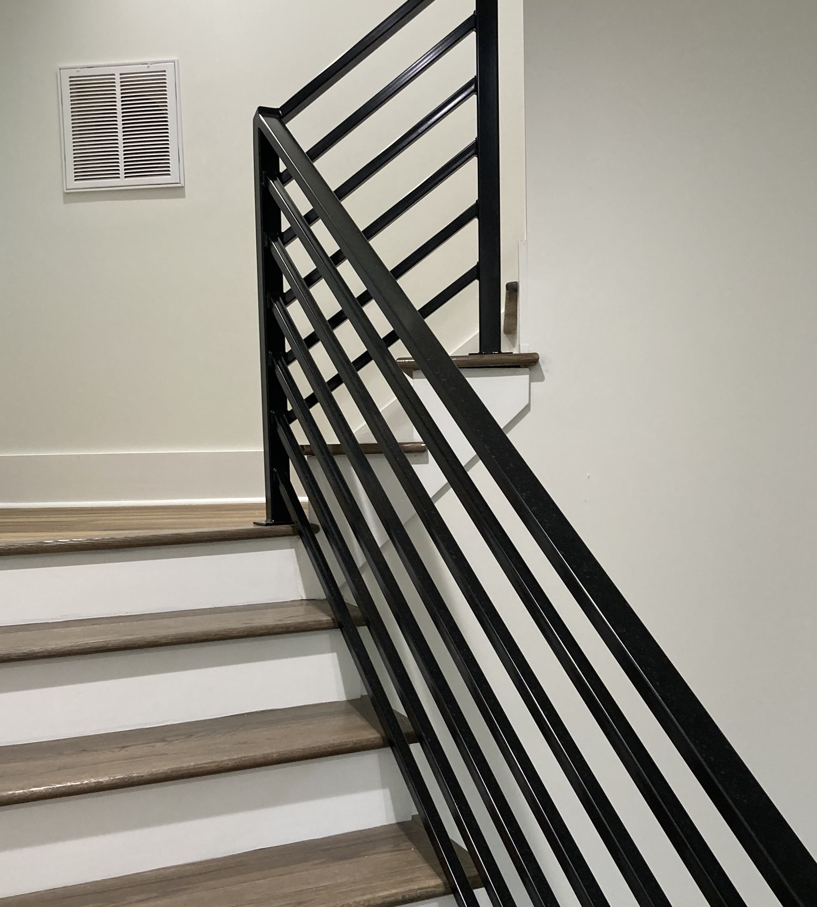 Interior stair run with glass railing panels, wood treads, and landing detail.
