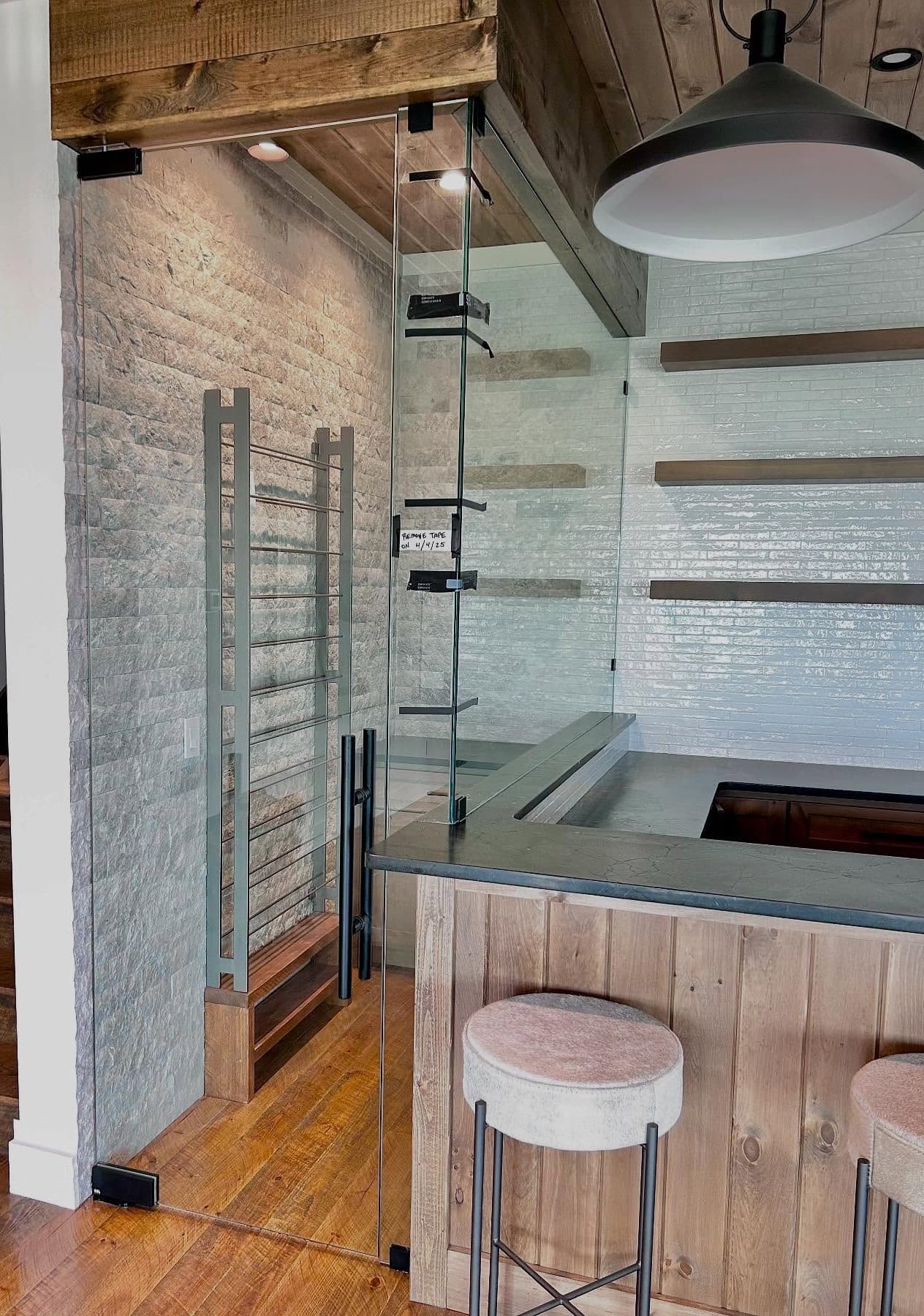 Wine cellar space with custom glass enclosure—empty tiled niche and clear panels.