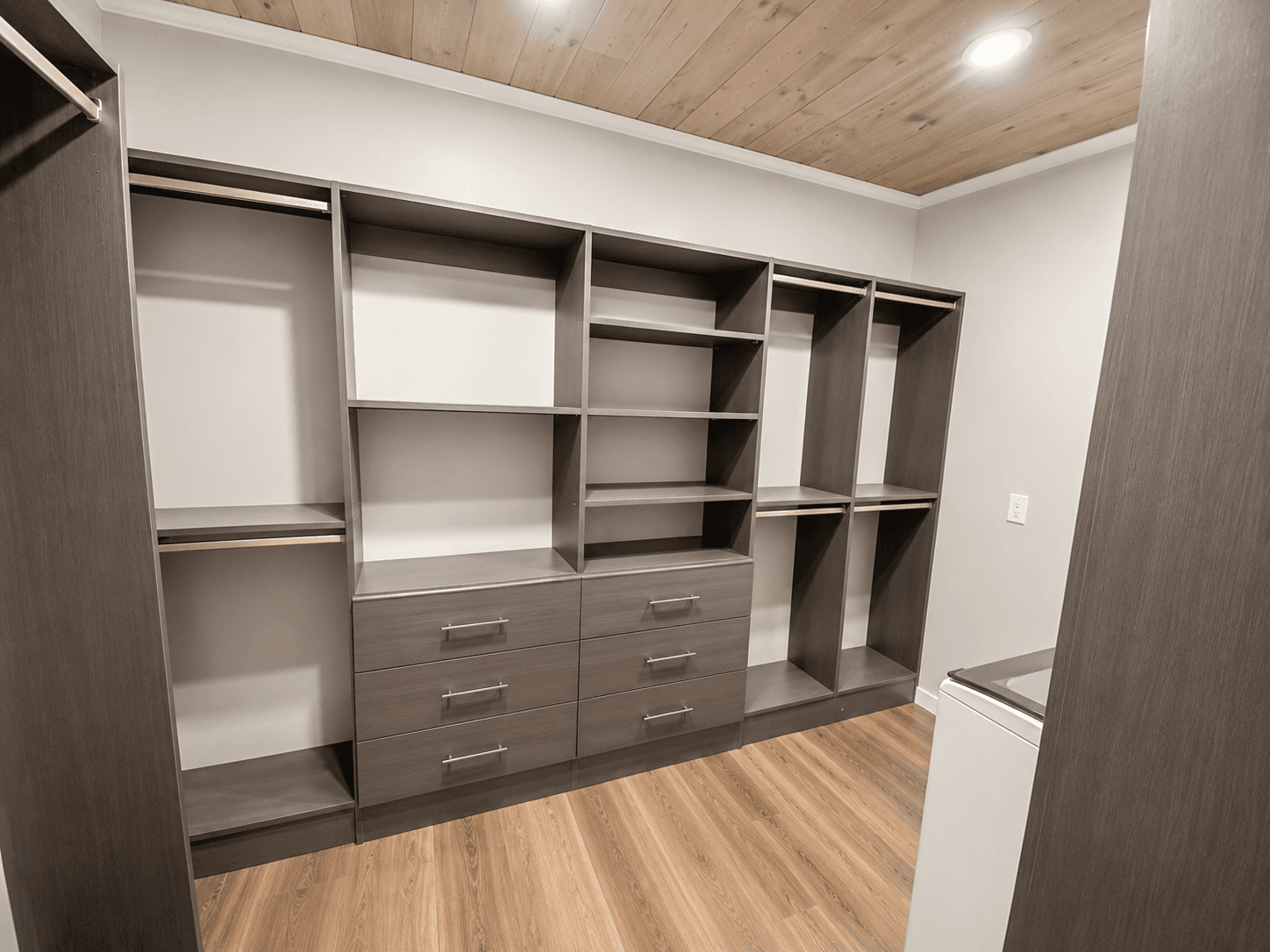 Custom walk-in closet organization system with drawers, shelves, and hanging rods.