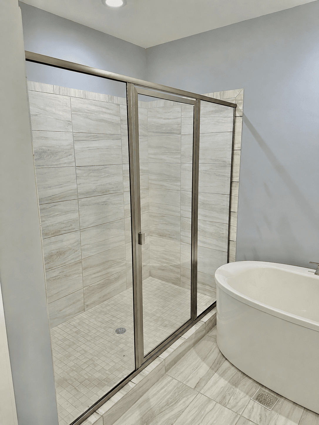 Replacement shower door glass and hardware on a residential bath.