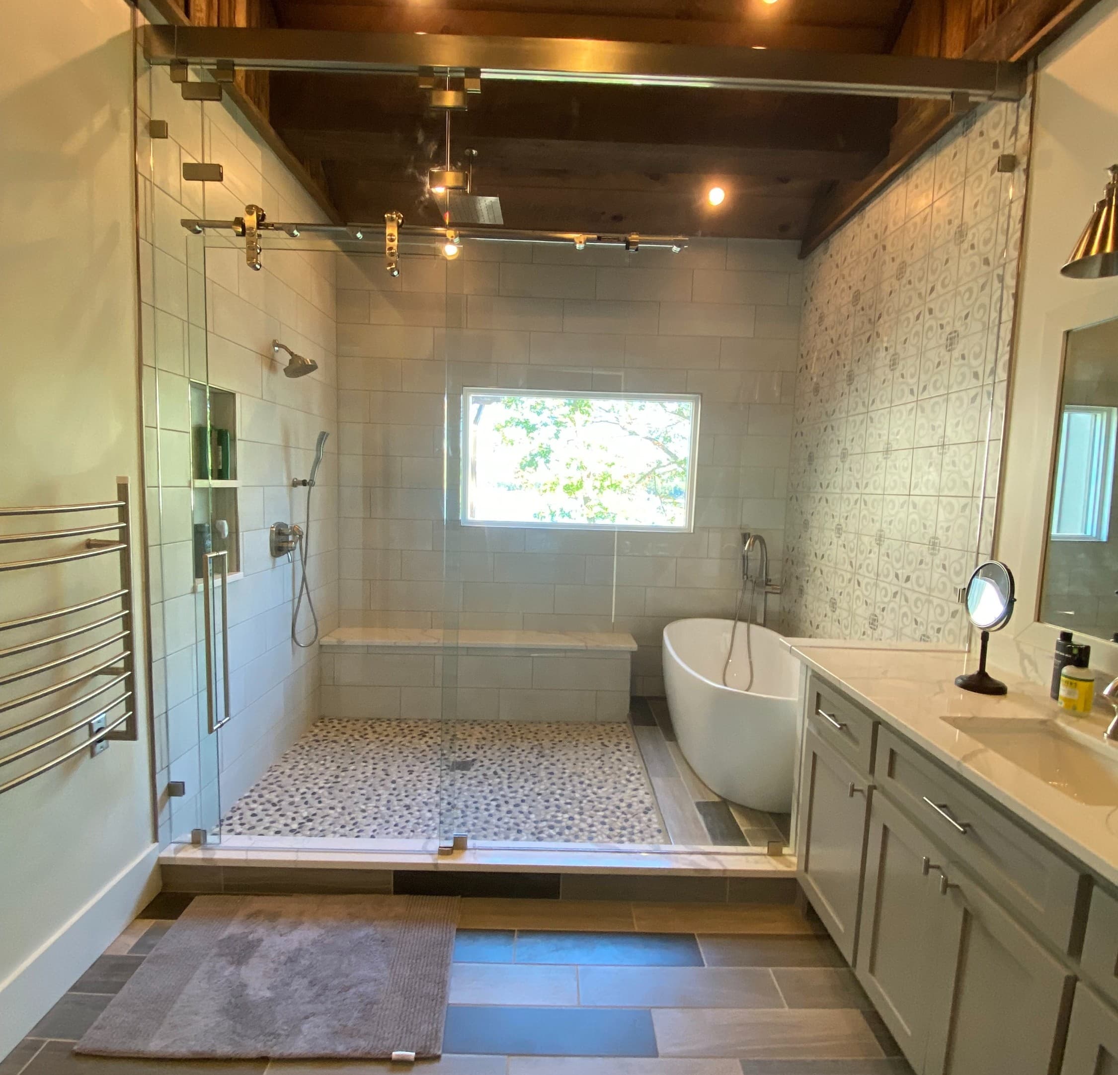 Frameless glass shower enclosure with sliding door and pebble shower floor.