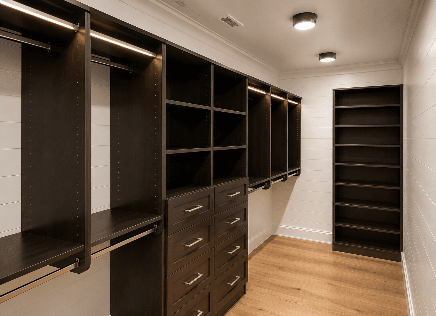 Custom walk-in closet with built-in shelving, hanging rods, and drawer storage in a finished room.