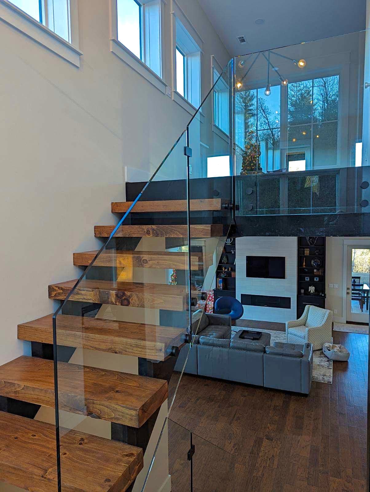 Glass railing system with clear panels and metal posts along a residential deck or stair opening.